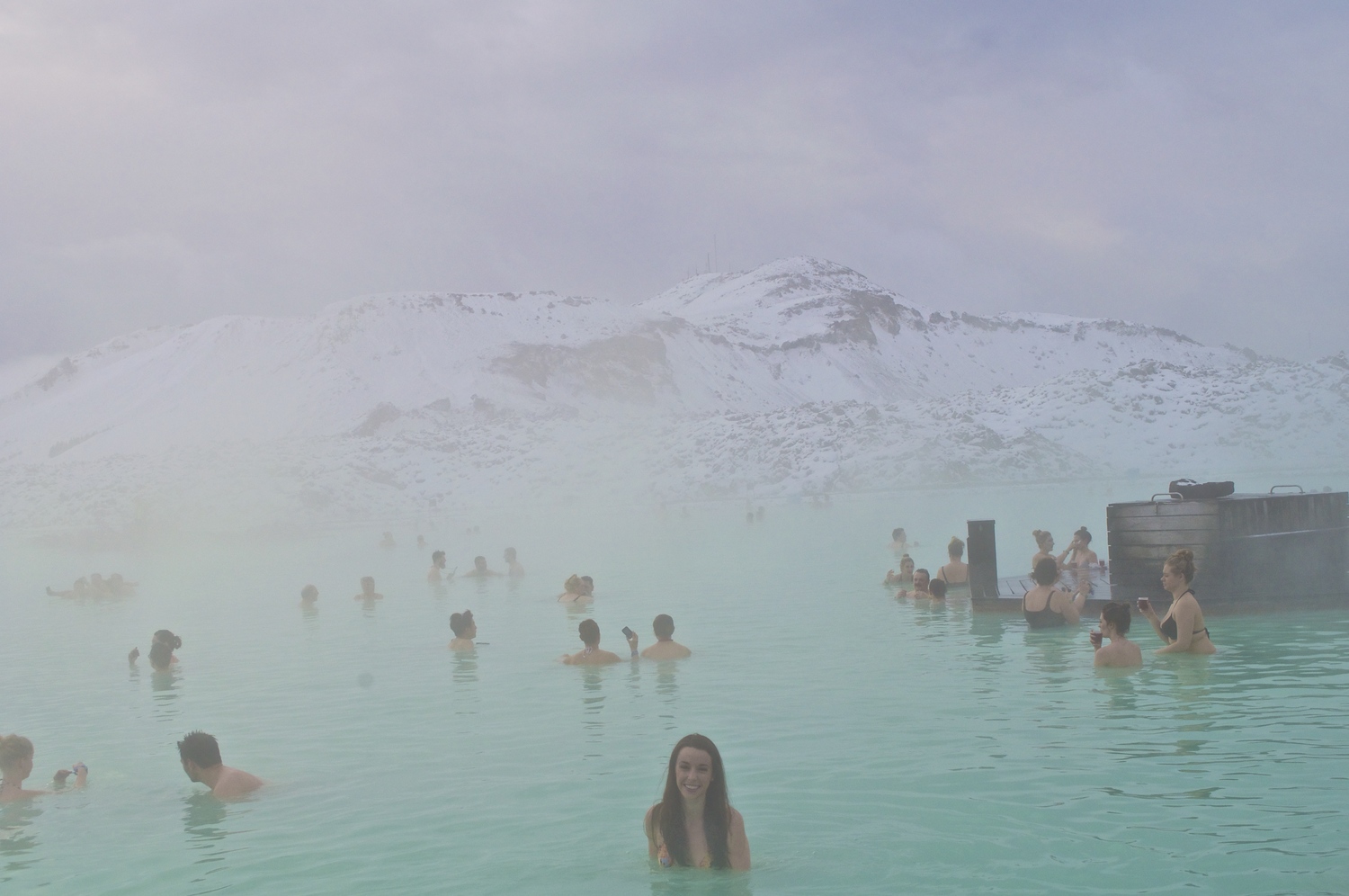 The blue lagoon is surrounded by lava fields covered in freshly fallen snow.