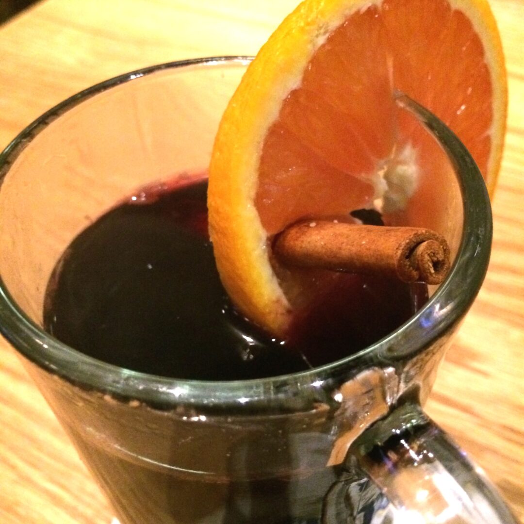 Gluwein (Warm German Christmas Wine) with a slice of orange and a cinnamon stick.