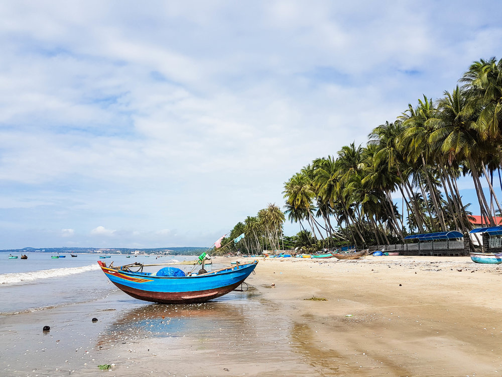 A fisherman's boat lies on the sandy beach of Mui Ne
